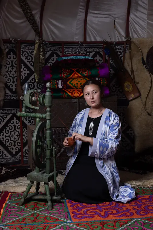 Woman at a spinning wheel inside a yurt